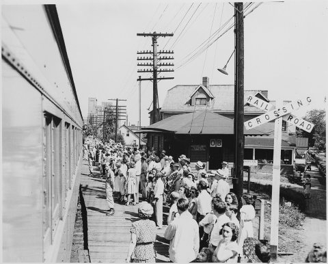 A crowd gathered at a railroad station, perhaps that at Bolivar, Missouri, to greet the presidential train. President..…