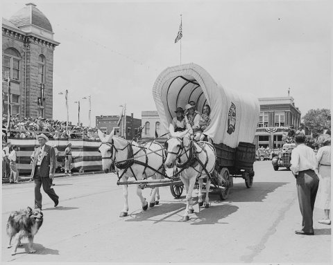 A covered wagon drawn by two white mules passes in front of the reviewing platform (in the distance) on which... - NARA…
