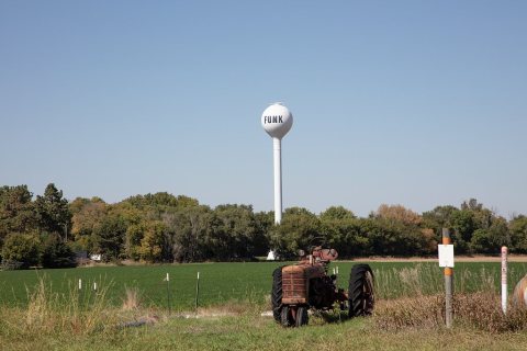 An old tractor sits below the town water tower