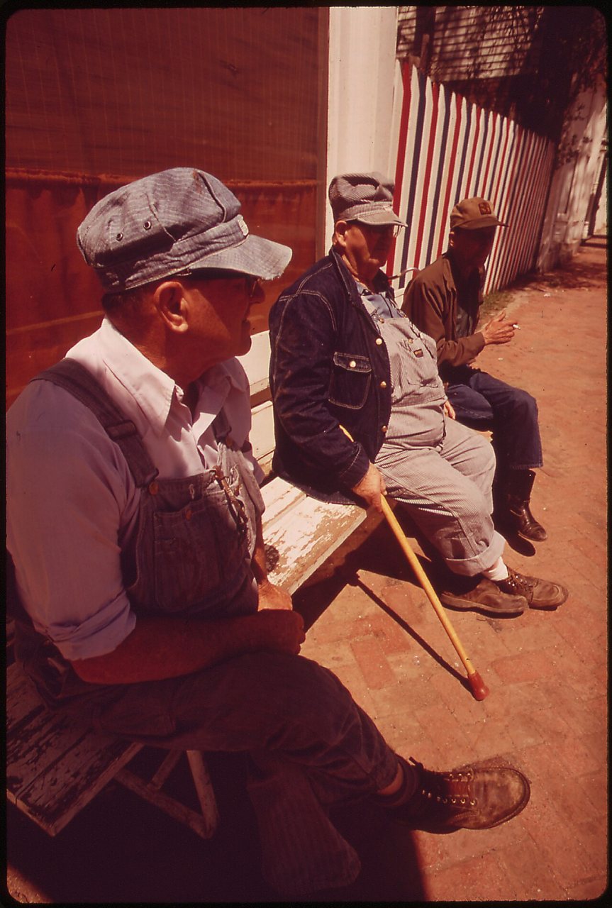 OLD MEN REST ON BENCHES FACING THE MAIN STREET OF