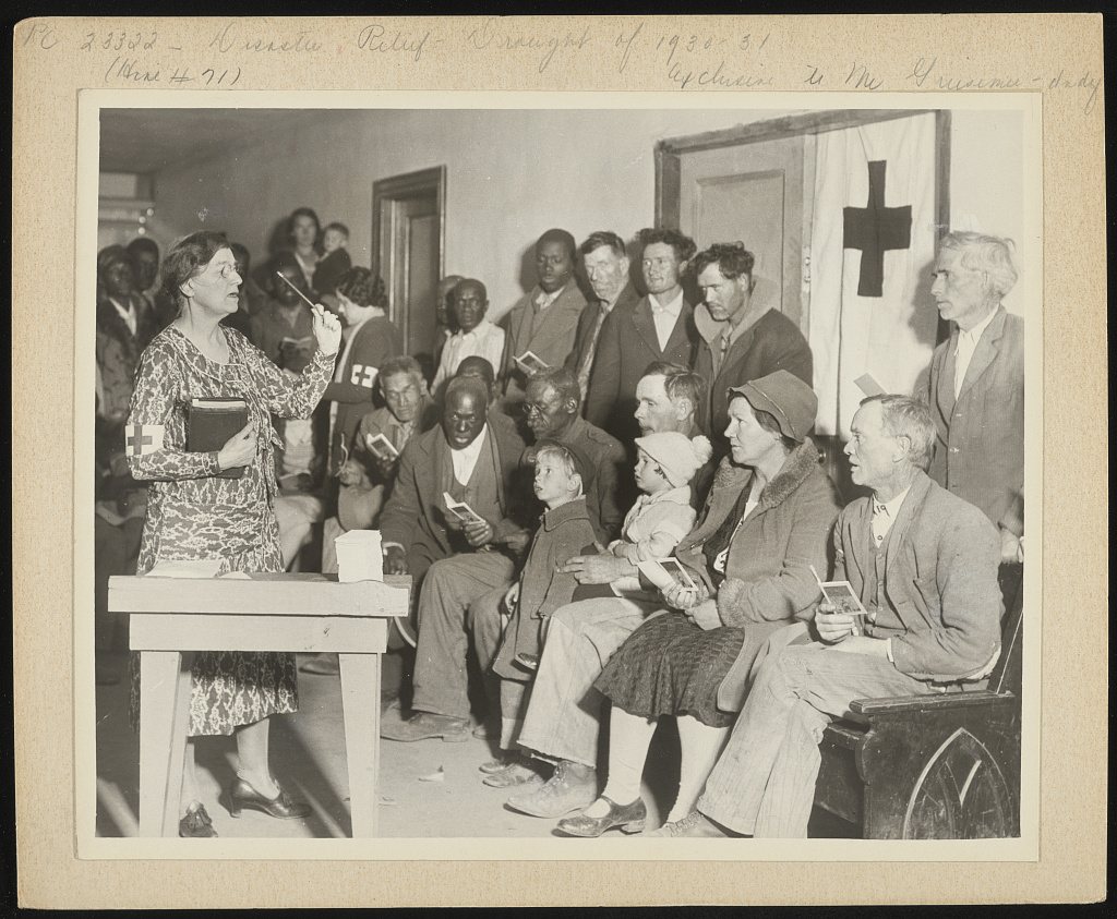 Applicants for Red Cross food orders while away the time in singing, instead of standing in line. The scene is at Lonok…