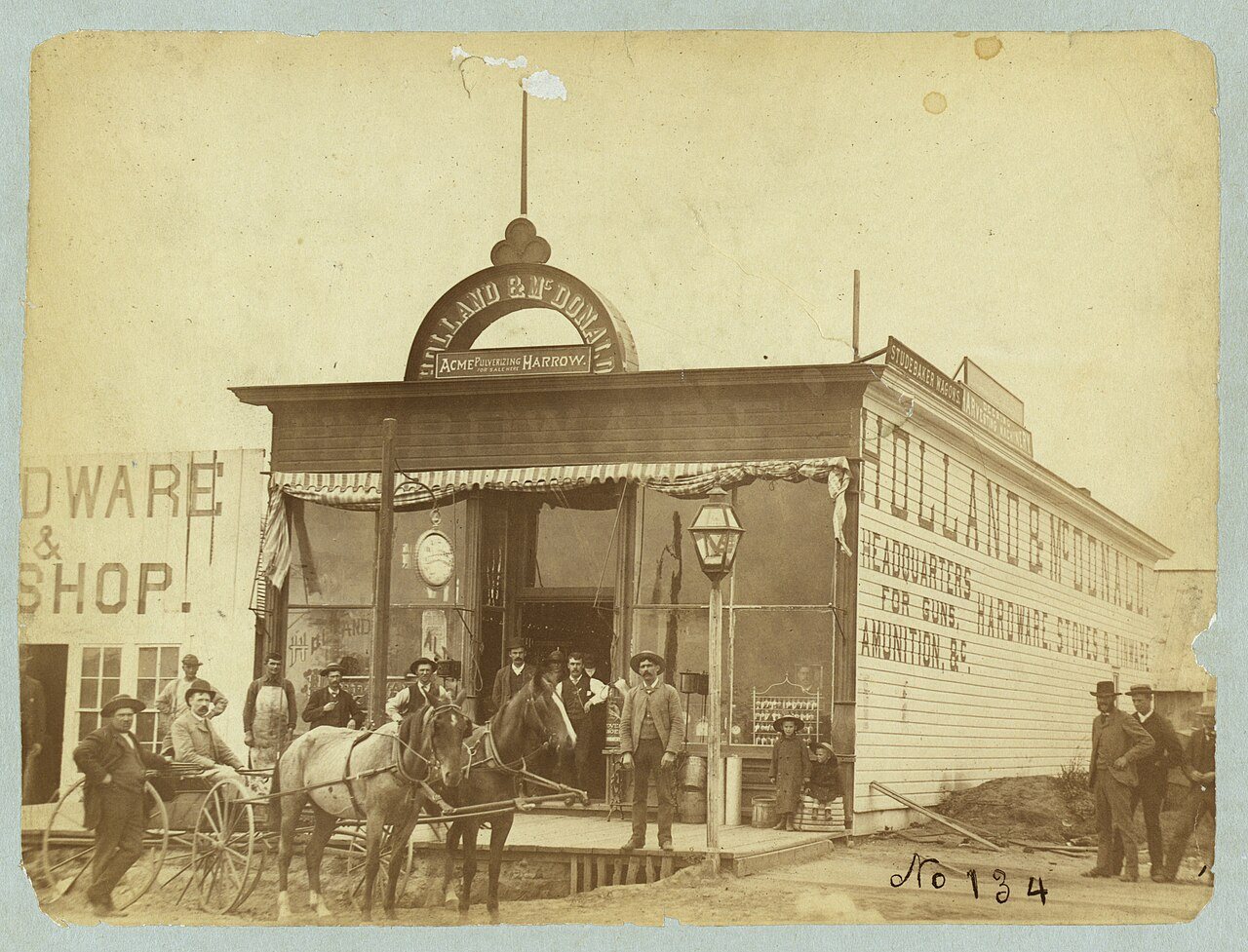 Group posed in front of the Holland & McDonald hardware store
