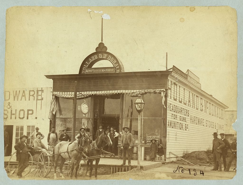 Group posed in front of the Holland & McDonald hardware store