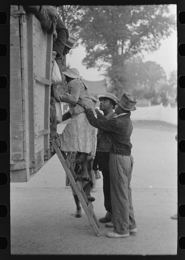 Helping women cotton pickers board truck
