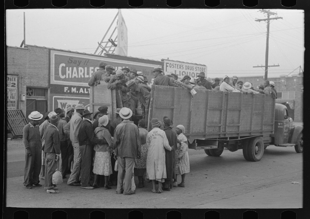 Cotton pickers boarding truck to take them to cotton fields