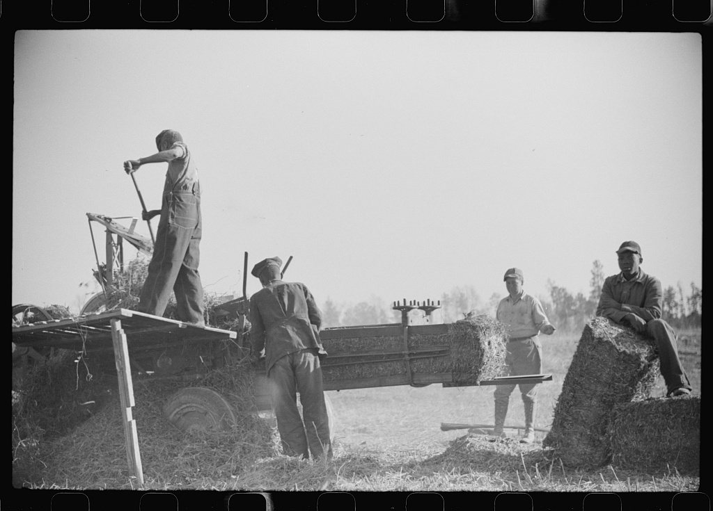Untitled photo, possibly related to: Baling hay on the Mary E. Jones place of about 140 acres. The sons W.E. and R.E. J…