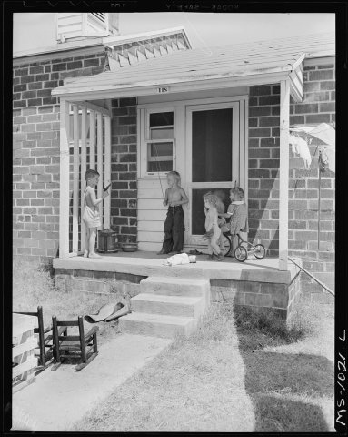 Front porch of home of government housing project now partially occupied by oil field workers. McCurtain, Le Flore Coun…