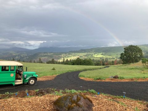 Rainbow above a vintage bus overlooking rolling hills