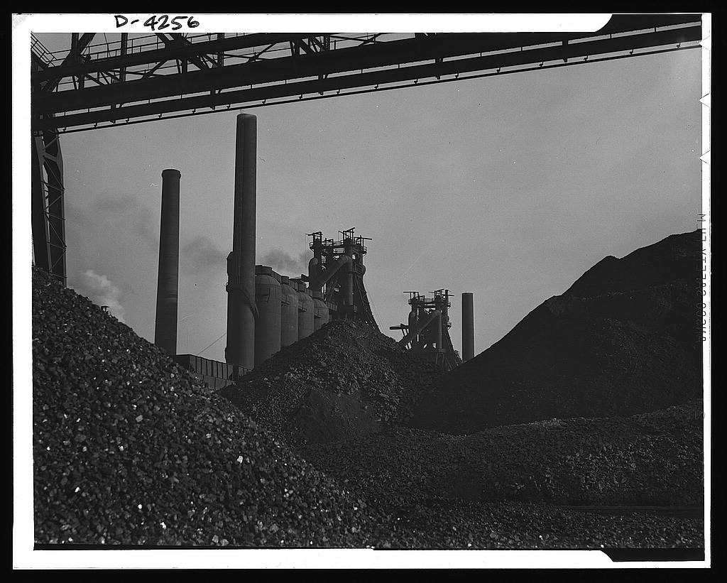 Steel production. The steel industry poised for wartime demands. Huge ore piles await feeding to hungry blast furnaces.…