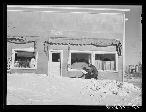 Shoveling snow in front of post office. Mission, South Dakota