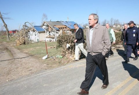 George W. Bush walks past rubble along a highway in