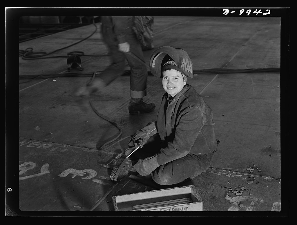 California shipyard workers. This woman worker pushes back her helmet during a moment's pause from her welding job at t…