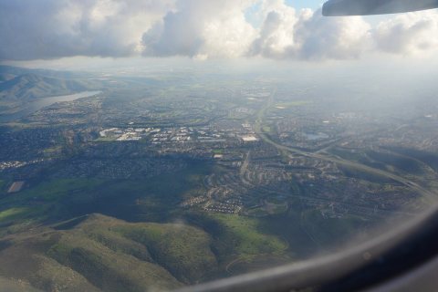 Aerial view of Lower Otay Lake, CA and towns to its west, looking south