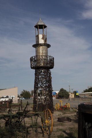 Metal art and agricultural equipment displayed across from the town museum