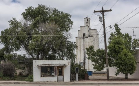 An isolated barber shop, and behind it the town grain elevator