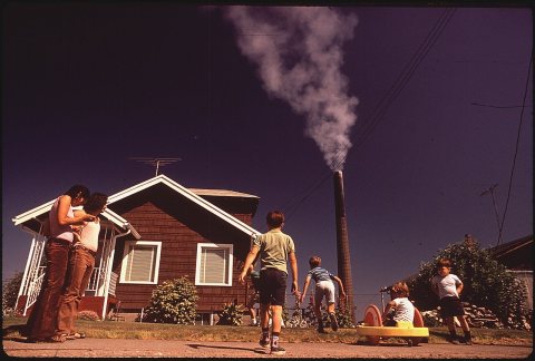 CHILDREN PLAY IN YARD OF RUSTON HOME, WHILE TACOMA SMELTER STACK SHOWERS AREA WITH ARSENIC AND LEAD RESIDUE