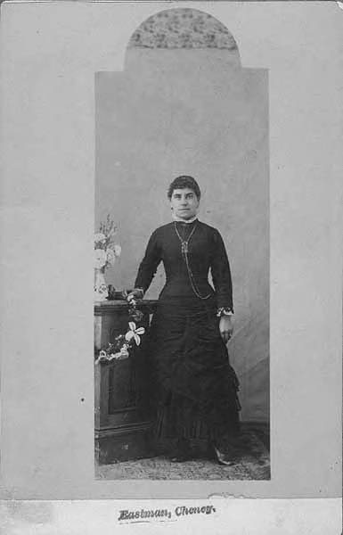Studio portrait of Mrs. Dow standing next to a table, Cheney, ca. 1884