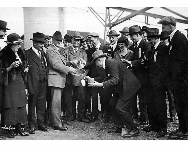 Two men with bucket of cider dispensing samples to group of men and women, Kennewick, October 1920