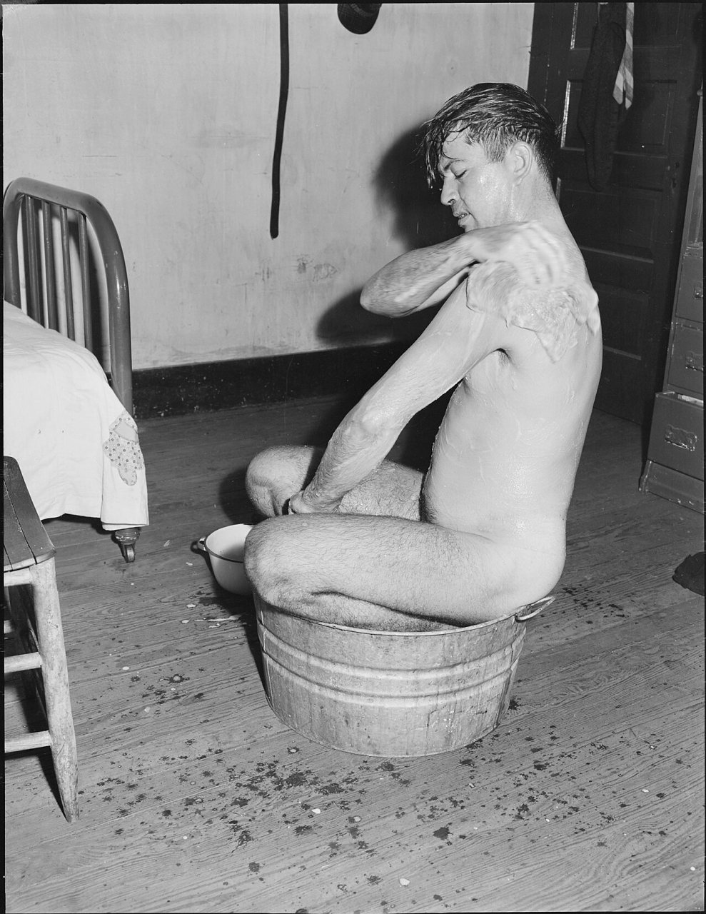 Milong Bond, tipple worker, taking a bath. He rents a three room house for $8 monthly, this fee does not include... - N…