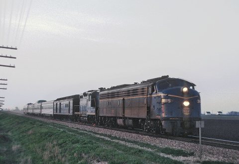 N&W E8A 3815 with Train 121, the domeliner Blue Bird, at speed north of Bement, Illinois at sunset on May 1, 1966