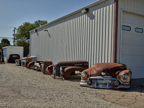 Hoods of old, rusted vehicles parked beside a shed for no perceptible reason in the little town of Annawan, Illnois