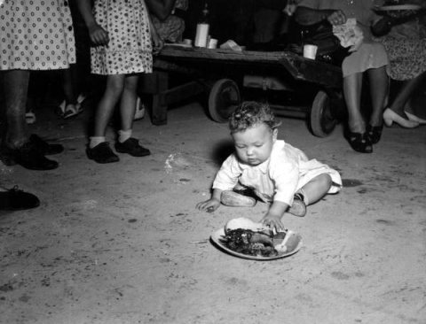 8-month-old Mary Odum eating off floor at dedication barbecue