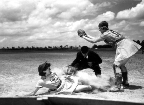All American Girls Professional Baseball League player Marg Callaghan sliding into home plate as umpire Norris Ward wat…