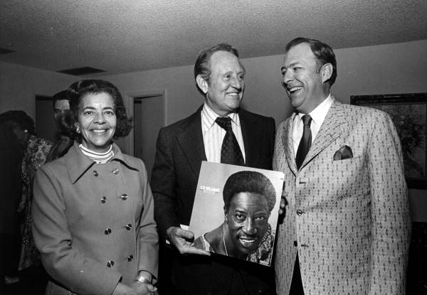 Art Linkletter holding a record by Joe Williams while standing with unidentified people