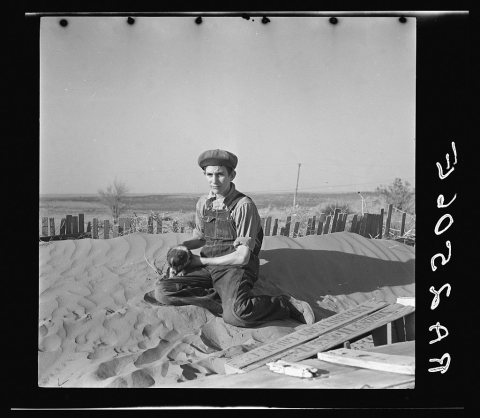 A farmer's son playing on one of the large soil drifts which threaten to cover up his home. Liberal, Kansas