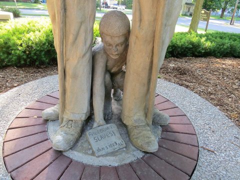 Slave Child kneeling at the feet of a Confederate soldier