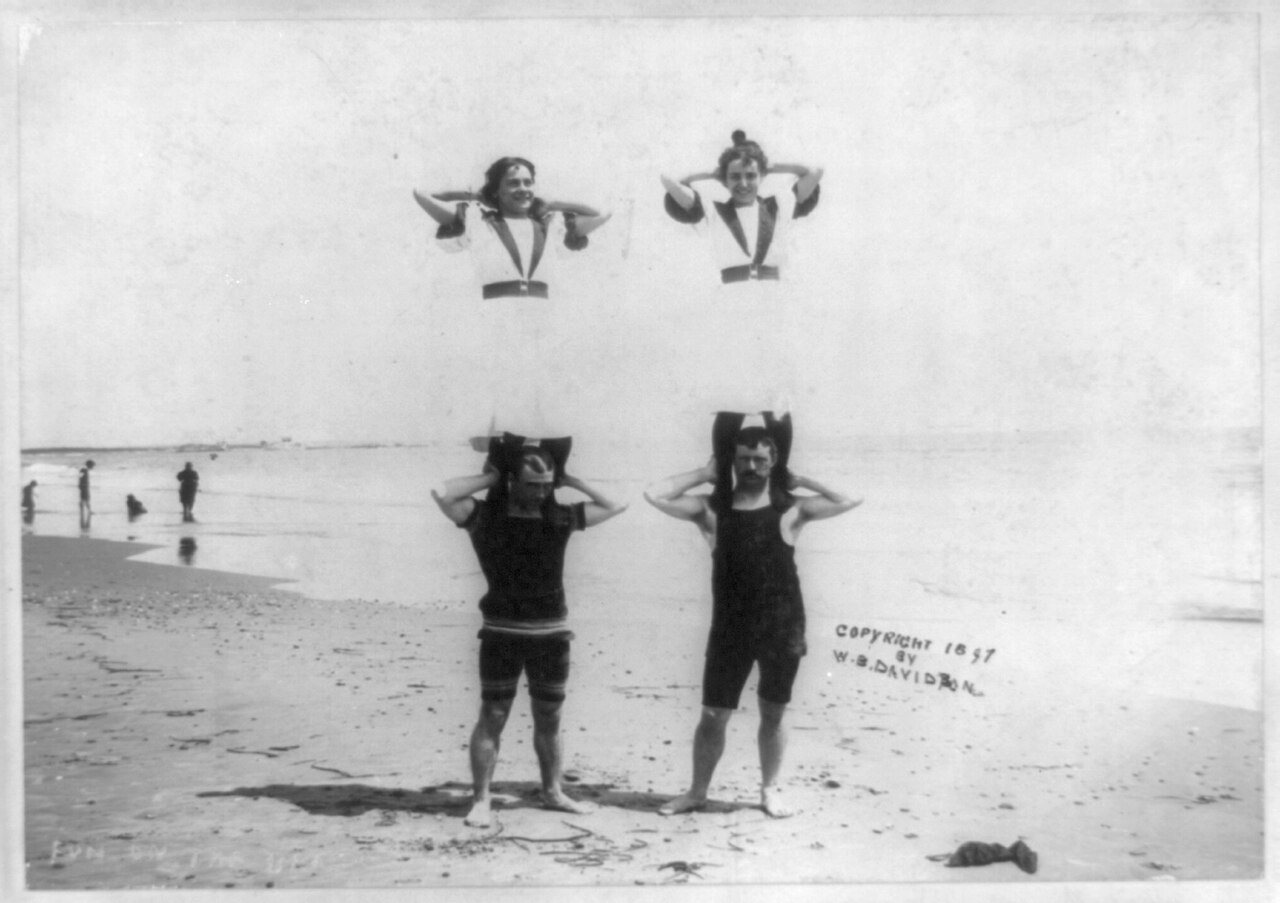 2 women standing on shoulders of 2 men on beach, R.I.?