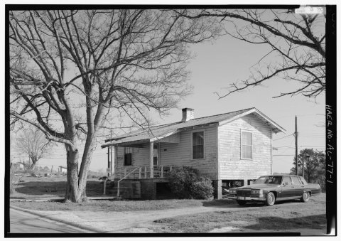 OBLIQUE VIEW, TCI TWO-ROOM HOUSE WITH STEEL ROOF AND ORIGINAL SIDING, FRONT PORCH, BRICK CHIMNEY, AND PIER FOUNDATIONS …