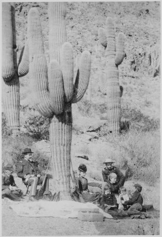 "Officers and guests lunch under giant cactus near Fort Thomas, Arizona." February 18, 1886
