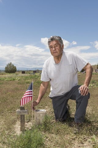 Rudy Tafoya places a small American flag near the headstone of a child who was buried in Chico Cemetery, a windswept co…