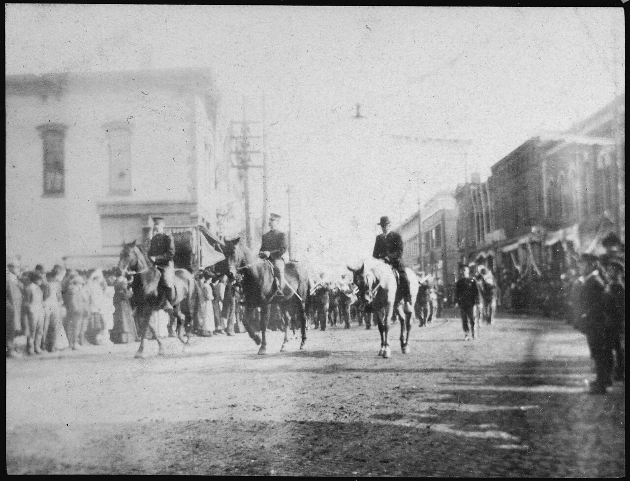 Photograph of men on horses and on foot in parade
