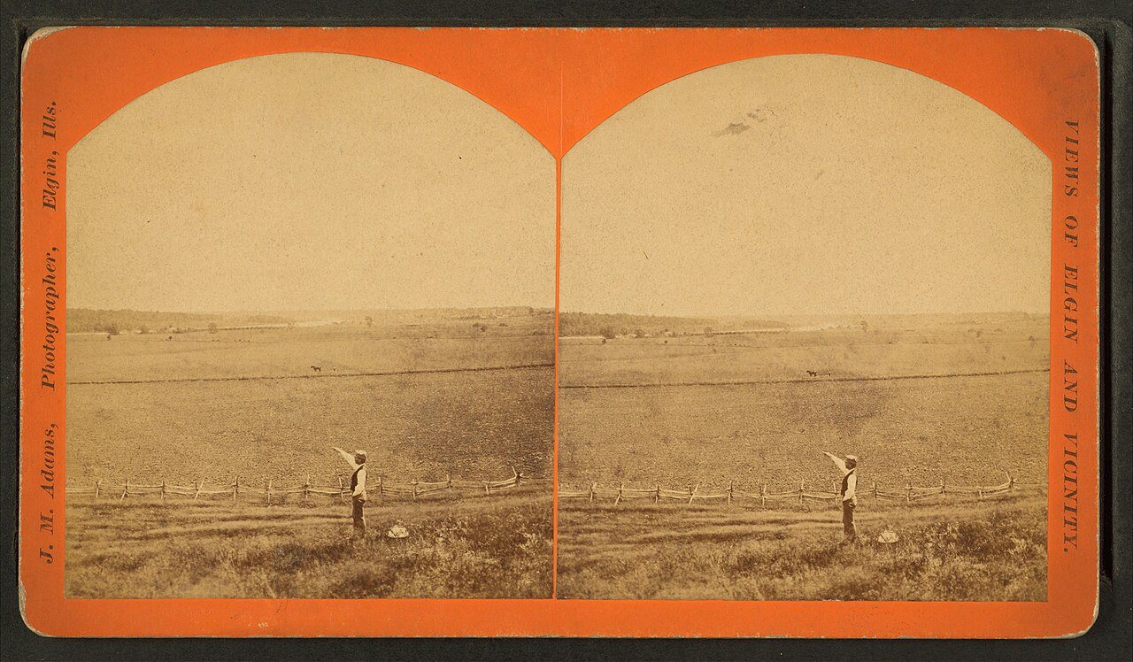 Man pointing over field surrounded by split rail fence that another man is plowing near Elgin.Alternate Title: Views of…