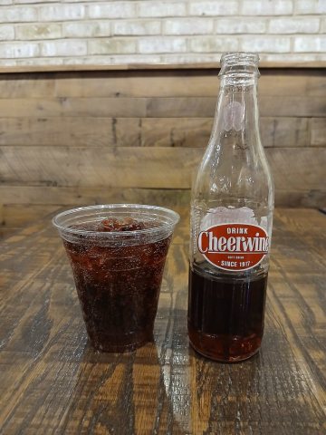 Bottle and plastic cup of Cheerwine at dinner