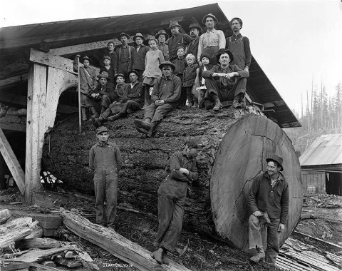 Group of men and children seated on large log, Startup, ca. 1925