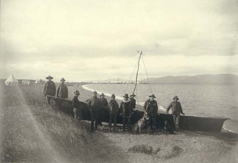 Men standing on the beach with umiak, or skin boat, Teller, Alaska, ca. 1900