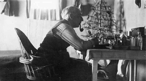 Roald Amundsen writing at a table and smoking a pipe, Wainwright, Alaska, 1922 or 1923