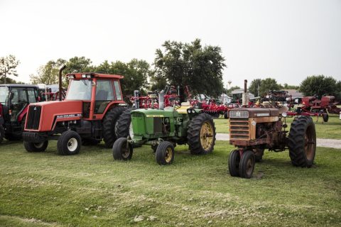Old and new tractors stand wheel by wheel at a farm-implement dealership