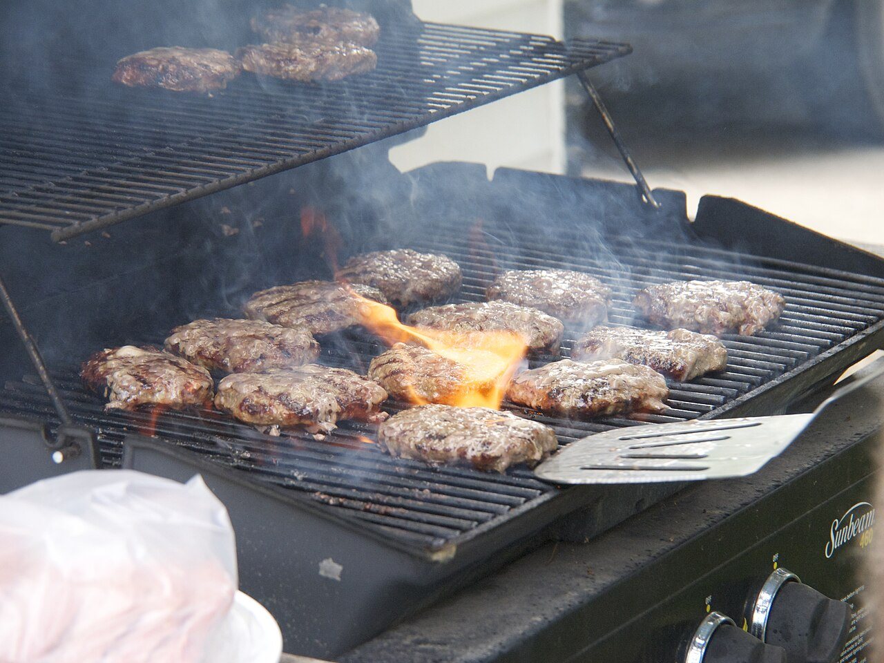 Hamburgers grilling outdoors over propane