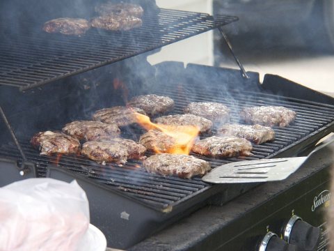 Hamburgers grilling outdoors over propane