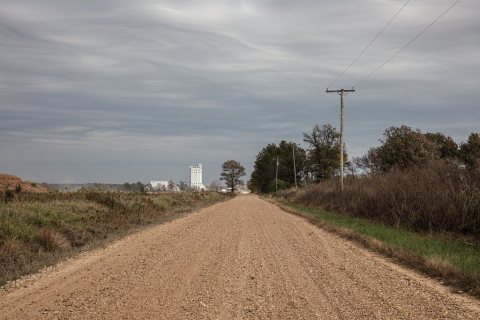 Gravel road leading to a distant grain elevator near the tiny town of Cash (a version of the name of the nearby Cache R…