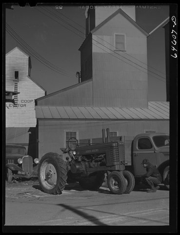 Dawson, Minnesota. Farmer inspecting a tractor