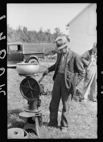 Farmer examining cream separator. Auction near Tenstrike, Minnesota