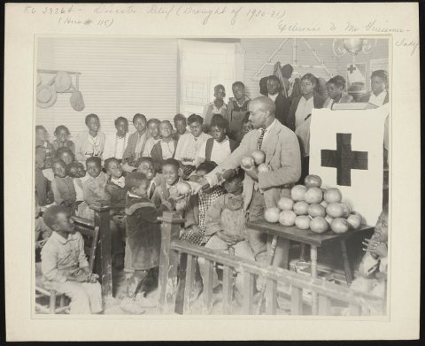 Typical colored school near Shaw, Mississippi. It is held in a church. The teacher is distributing fruit sent to the Re…