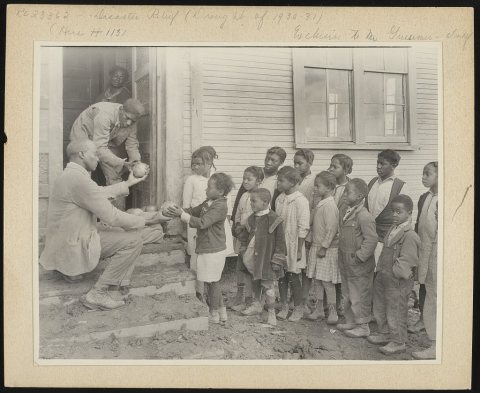 Typical colored school near Shaw, Mississippi. It is held in a church. The teacher is distributing fruit sent to the Re…