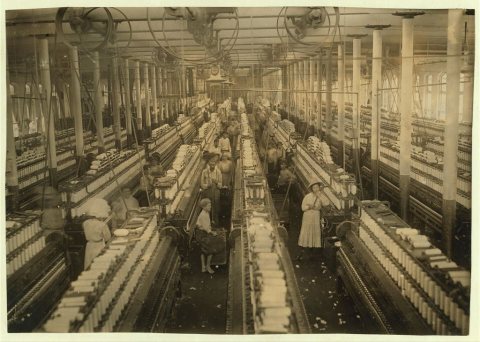 Interior of Magnolia (Miss) Cotton Mills spinning room. See the little ones scattered through the mill. All work. See a…
