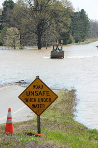FEMA - 34605 - A resident drives a tractor across a flooded road in Arkansas